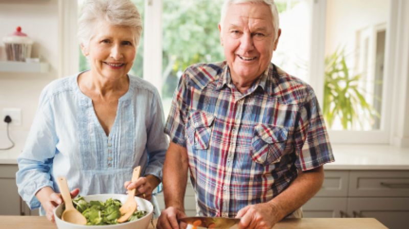 Senior couple smiling in front of counter with healthy foods 
