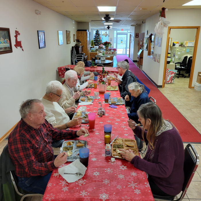 Seniors dining at long table with red tablecloth