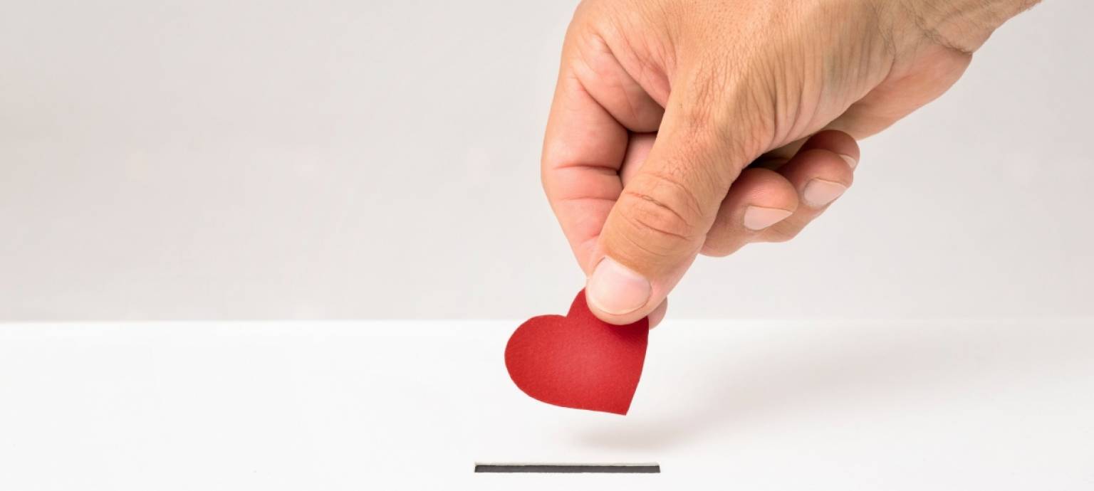 close up of hand putting a heart in a donation box